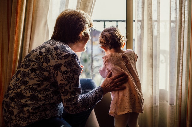 elderly woman and her grandchild looking out a window